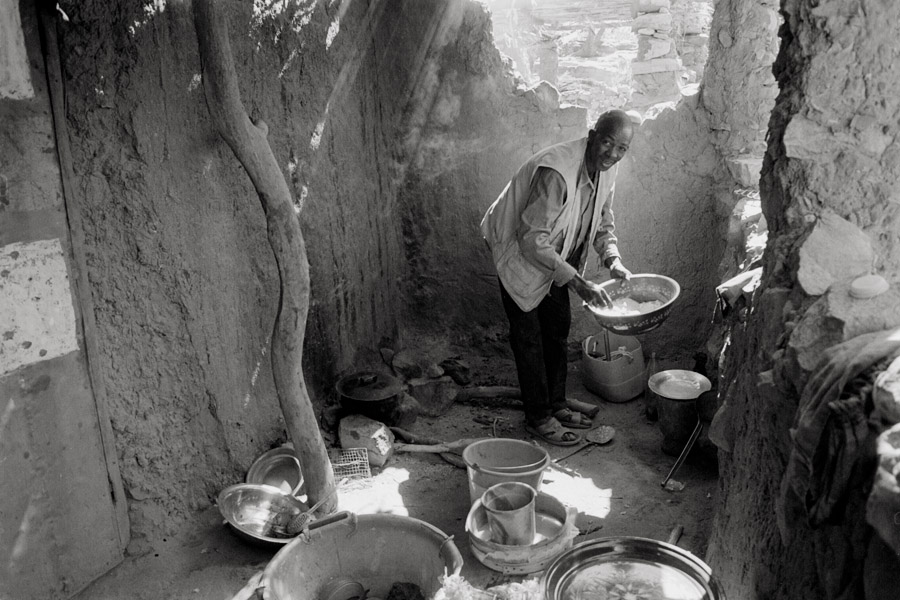 Konsongo, Mali (Dogon Country) 2010: Abel cooks lunch for trekkers at his village camp. Food is cooked over a wood fire and can often take more than an hour to prepare.